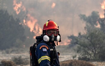A firefighter looks on during a fire near the village of Vati, just north of the coastal town of Gennadi, in the southern part of the Greek island of Rhodes