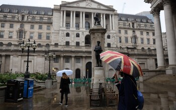 A woman carrying a Union Flag umbrella stands near the Bank of England 