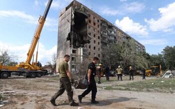 Rescuers carry a fragment of missile outside a nine-storey residential building partially destroyed as a result of Russian missiles strike 
